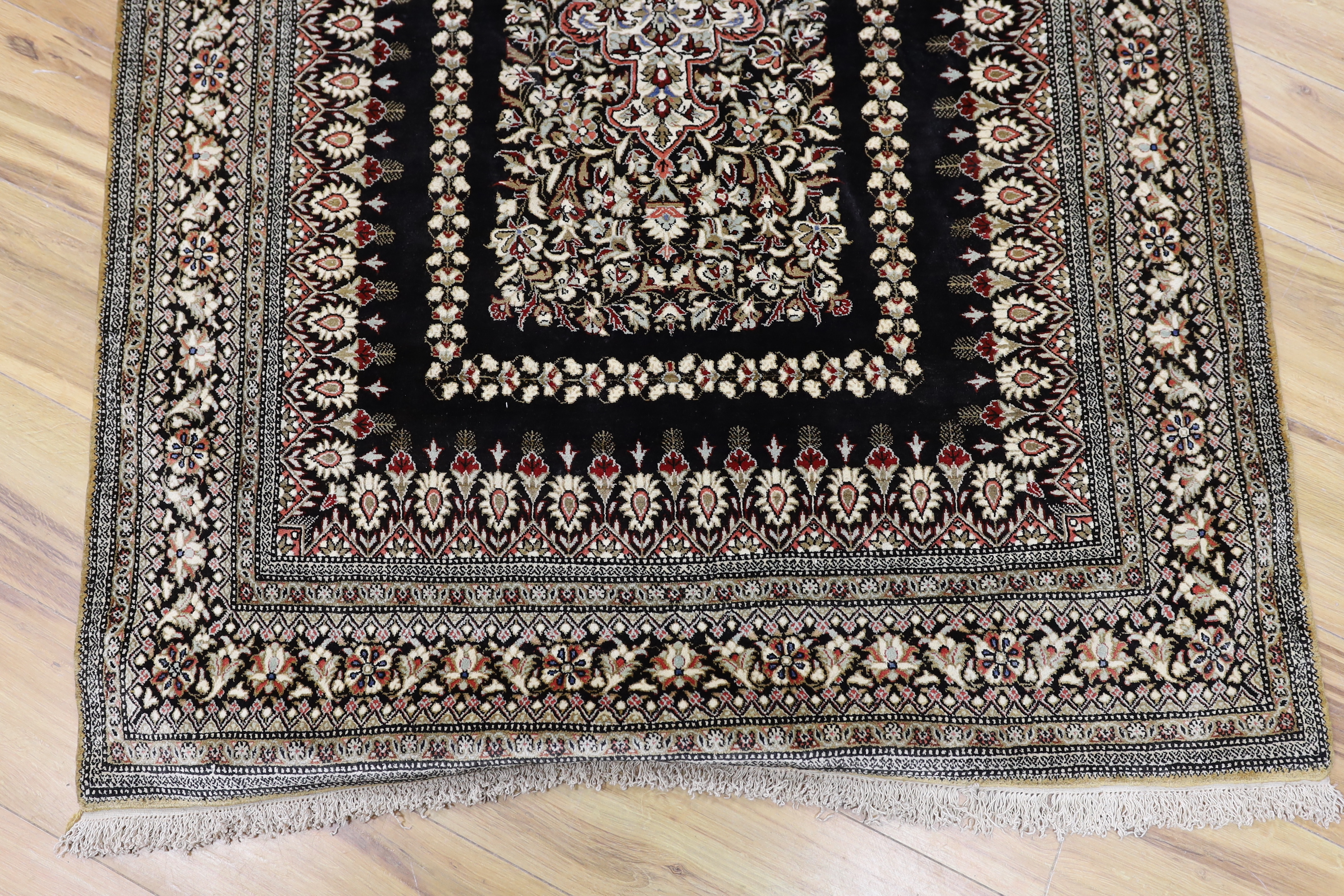 A Persian Qum silk rug, mounted as a wall hanging on a brass rod, 168 x 105cm